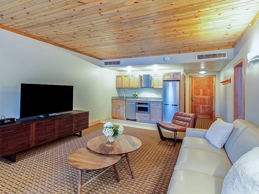 A modern living room with a flat-screen TV, a wooden entertainment unit, a round coffee table, and a sofa.