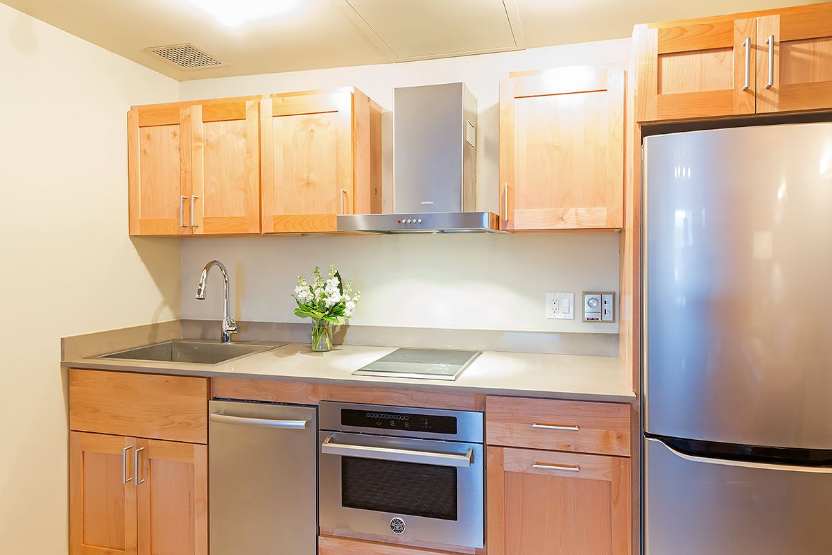 A modern kitchen with wooden cabinets, stainless steel appliances, and a built-in oven.