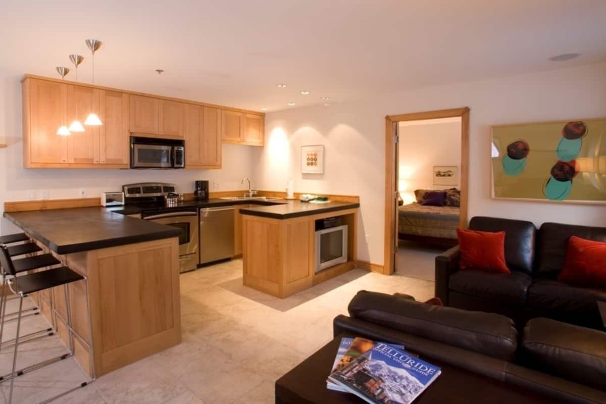 Una cocina moderna con armarios de madera, una isla central y una zona de comedor con taburetes de bar.