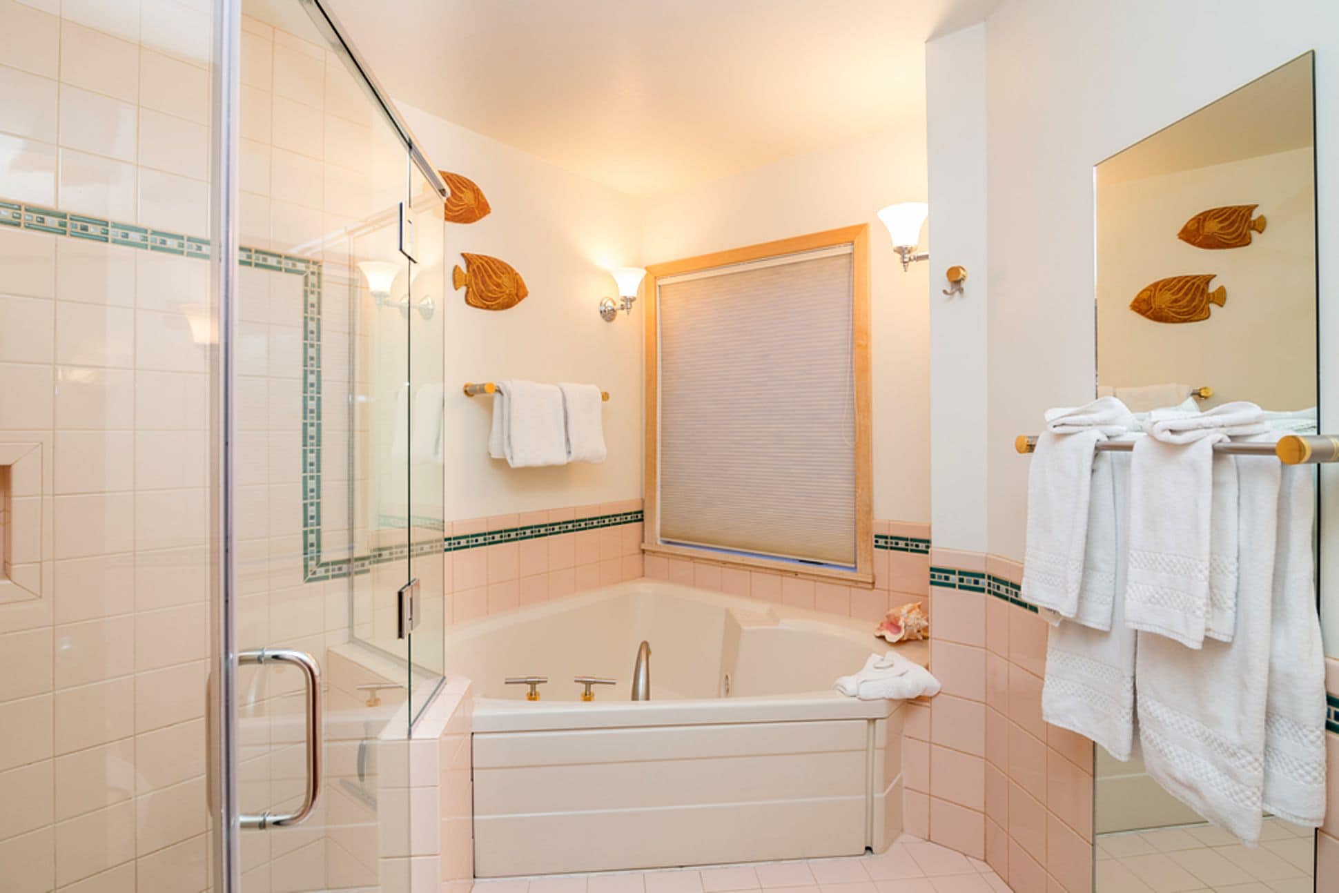 Une salle de bain moderne dotée d’une douche à parois de verre, d’une baignoire sur pied et d’un grand miroir agrémenté d’une décoration murale représentant des poissons.