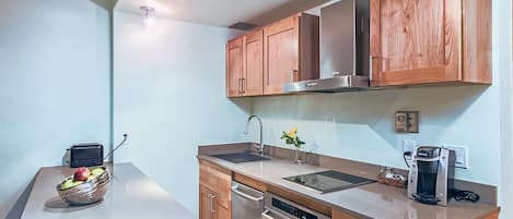 A modern kitchen with wooden cabinets, stainless steel appliances, and a bowl of fruit on the counter.