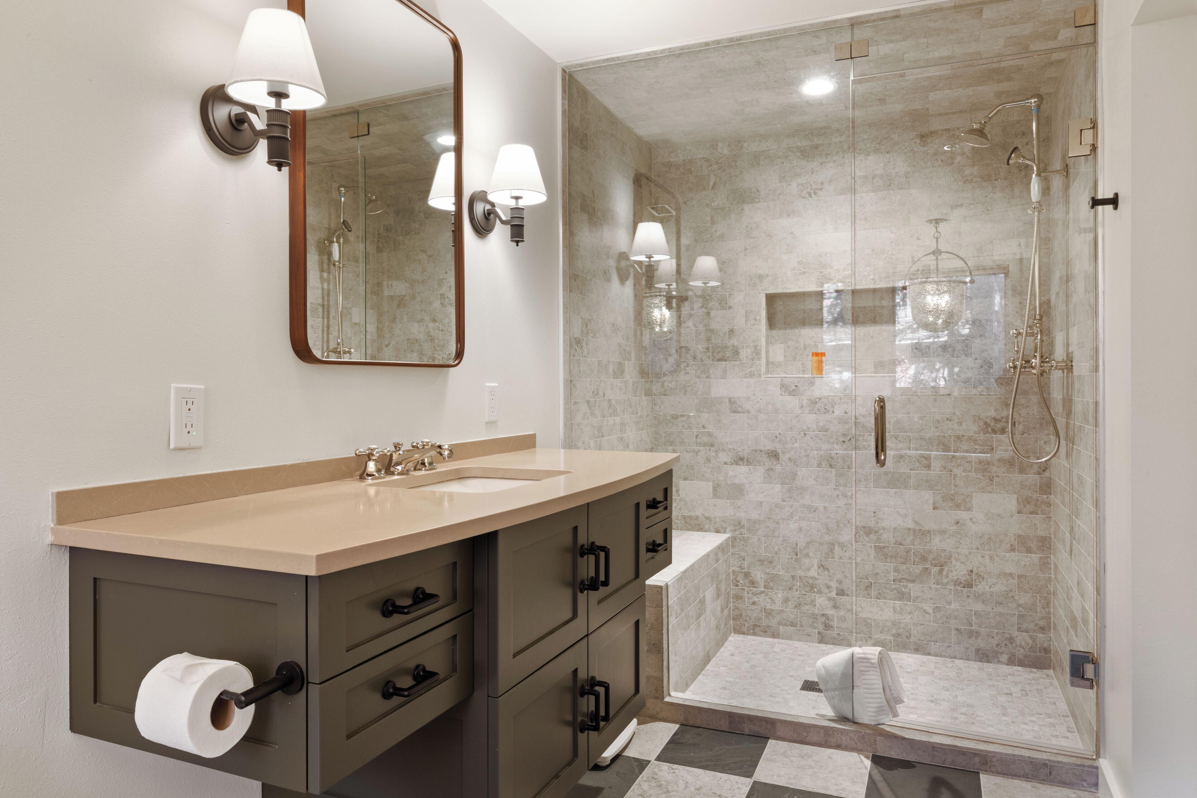 A modern bathroom with a beige vanity, a large mirror, and a glass-enclosed shower area.