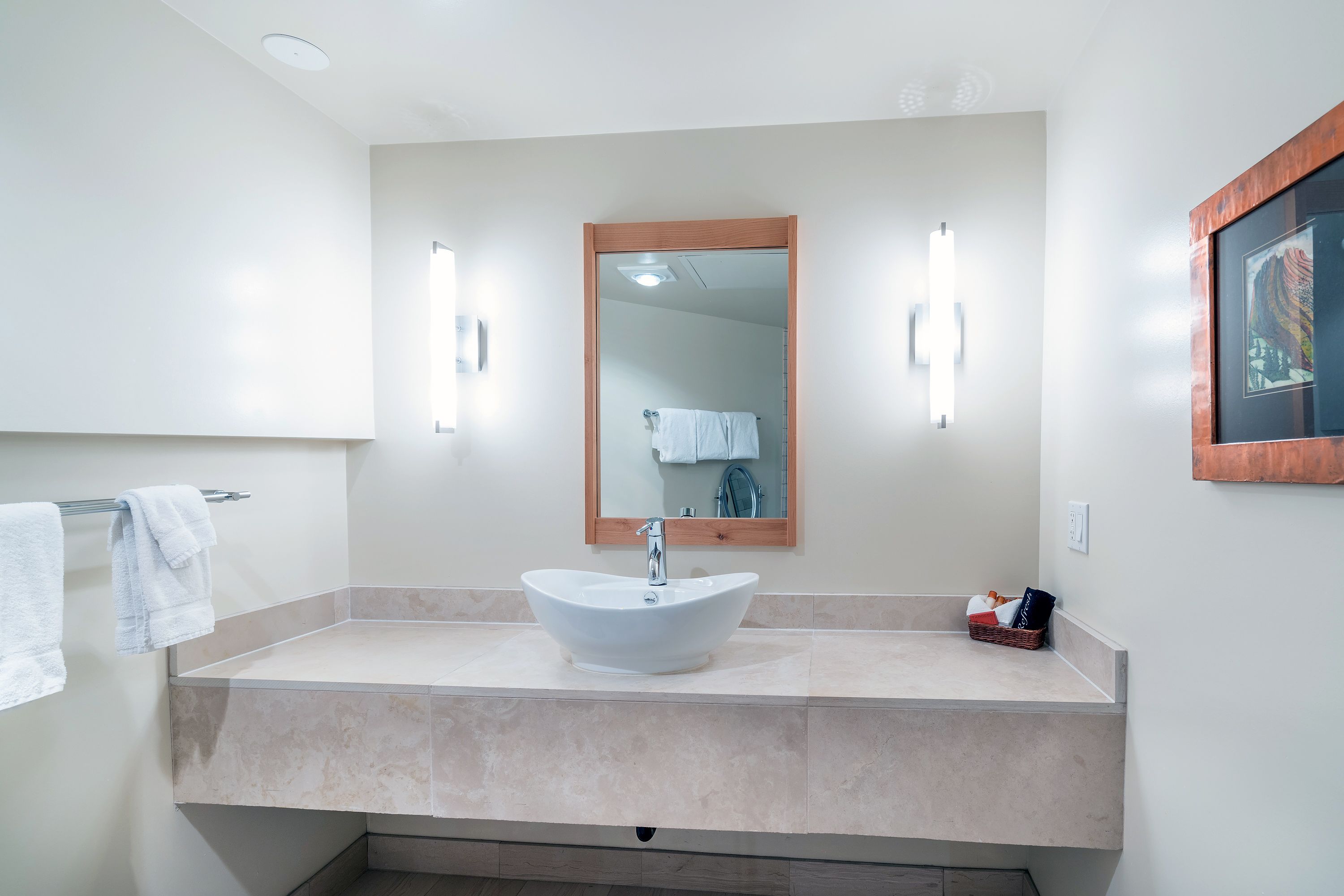A bathroom with a white sink, a mirror, and a towel rack.
