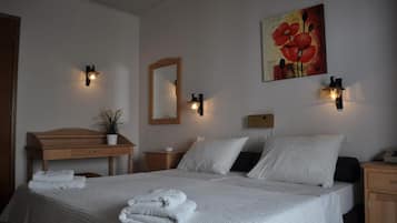 Quarto de hotel com cama, mesas de cabeceira, cômoda de madeira, espelho e luminárias na parede.