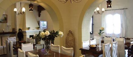 A dining area with a wooden table, white chairs, and chandeliers.