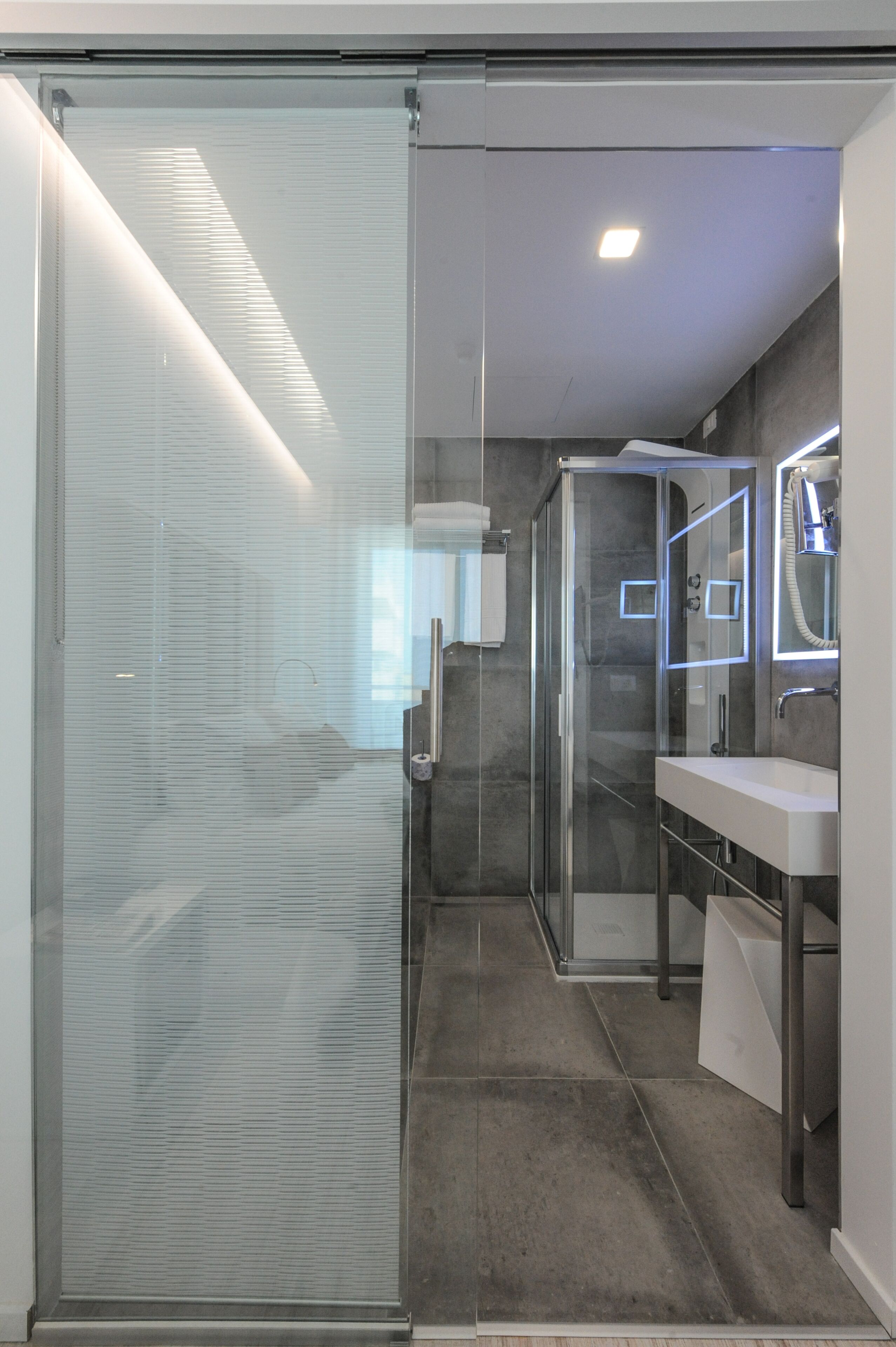 A modern bathroom with a glass shower enclosure, a white sink, and a mirror.