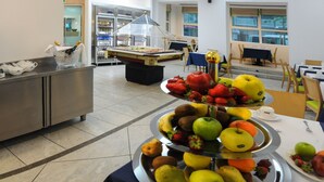 A buffet area with a fruit display and a pool table in the background. - Hotel Lampara (Lignano Sabbiadoro)