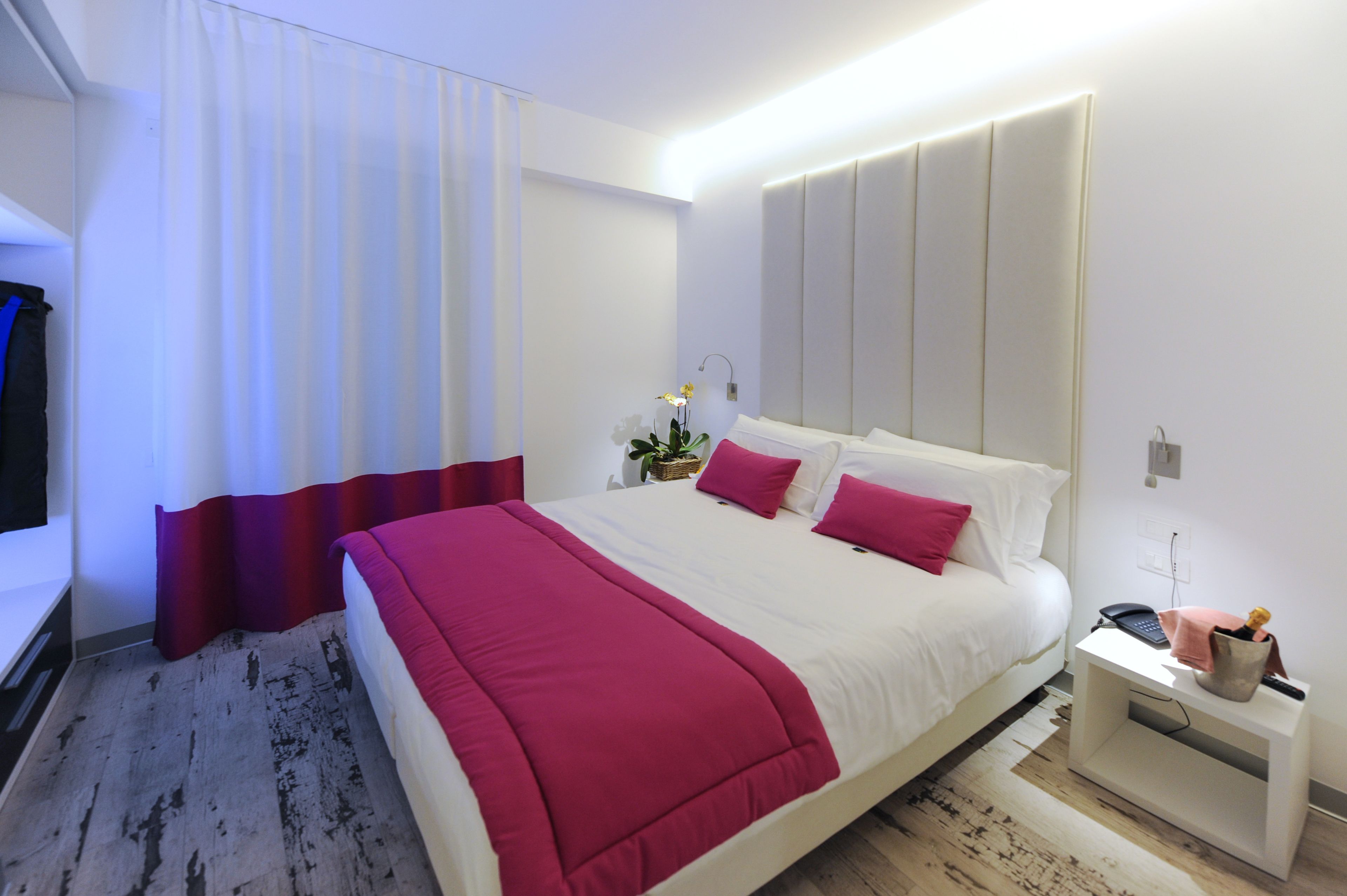 A modern hotel room with a large bed, a bedside table, and a nightstand.