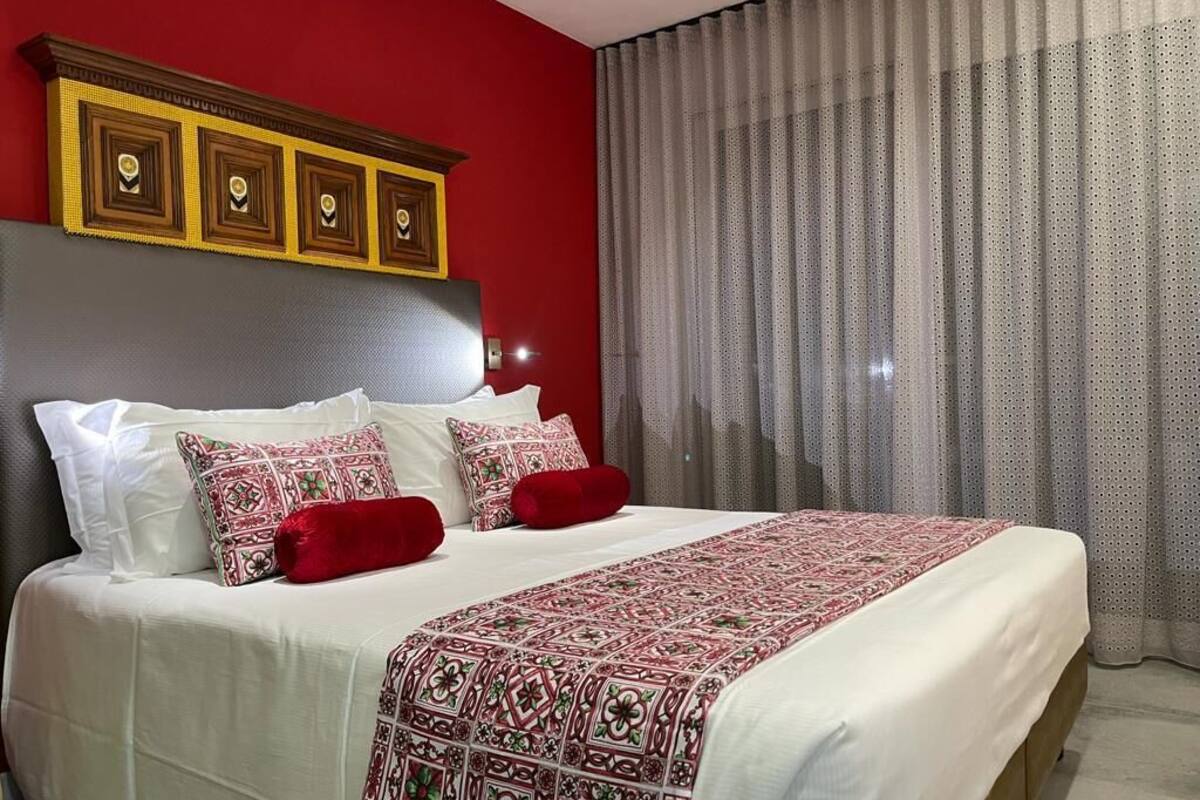 Een hotelkamer met een groot bed, rode wanden en een klassiek hoofdeinde.