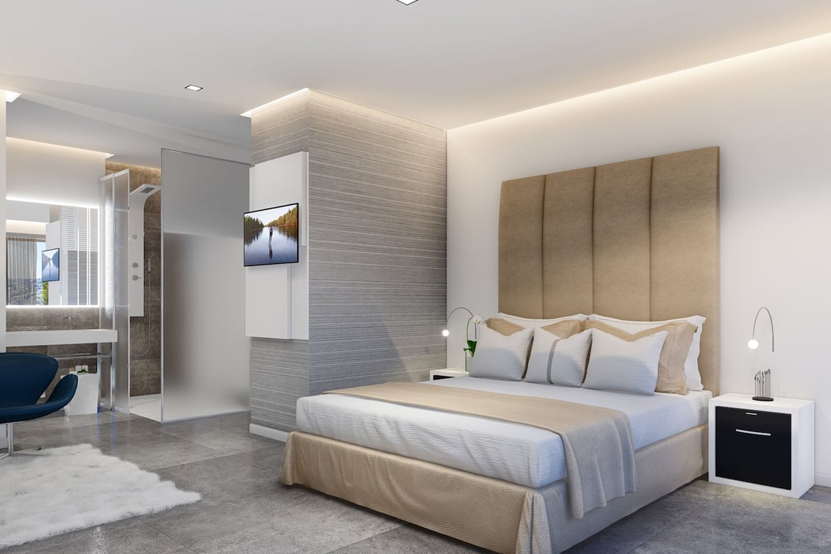 Een moderne slaapkamer met een groot bed, nachtkastjes, een televisie en een inloopkast.