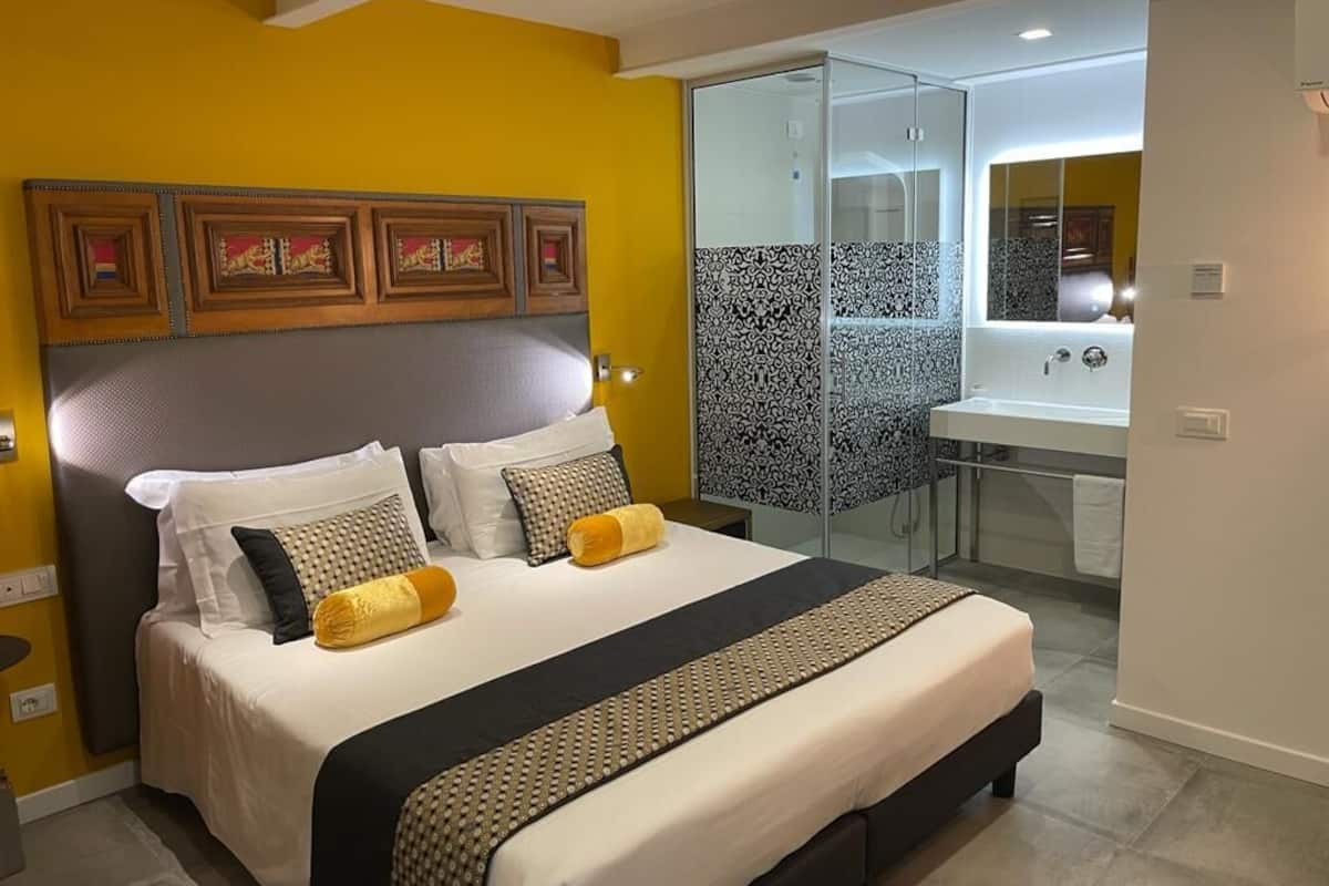 Een moderne hotelkamer met een groot bed, een douchecabine van glas en een kleine badkamer.