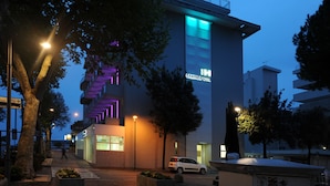 A modern hotel with a prominent staircase and illuminated signage. - Hotel Lampara (Lignano Sabbiadoro)