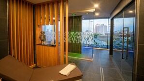 A modern hotel lobby with a reception desk, a trophy on display, and a view of the city through large windows. - Hotel Lampara (Lignano Sabbiadoro)