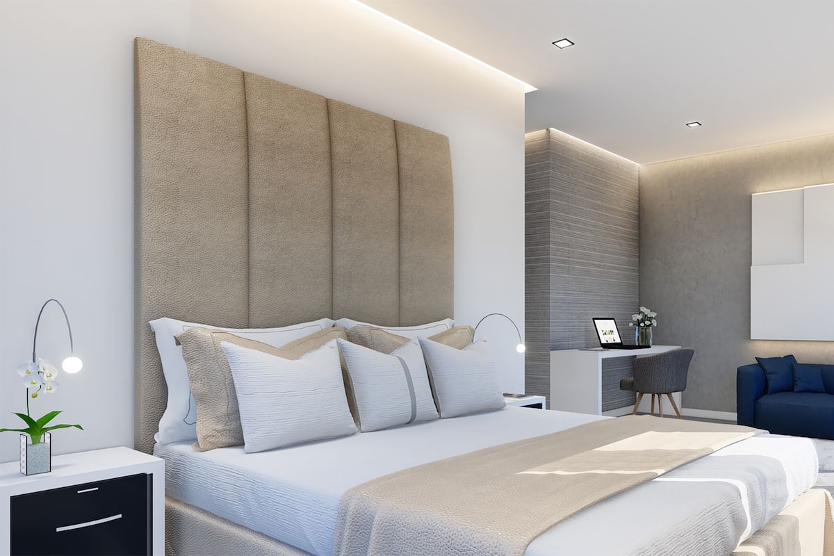Een moderne slaapkamer met een groot bed, nachtkastjes, een bureau en een blauwe bank.