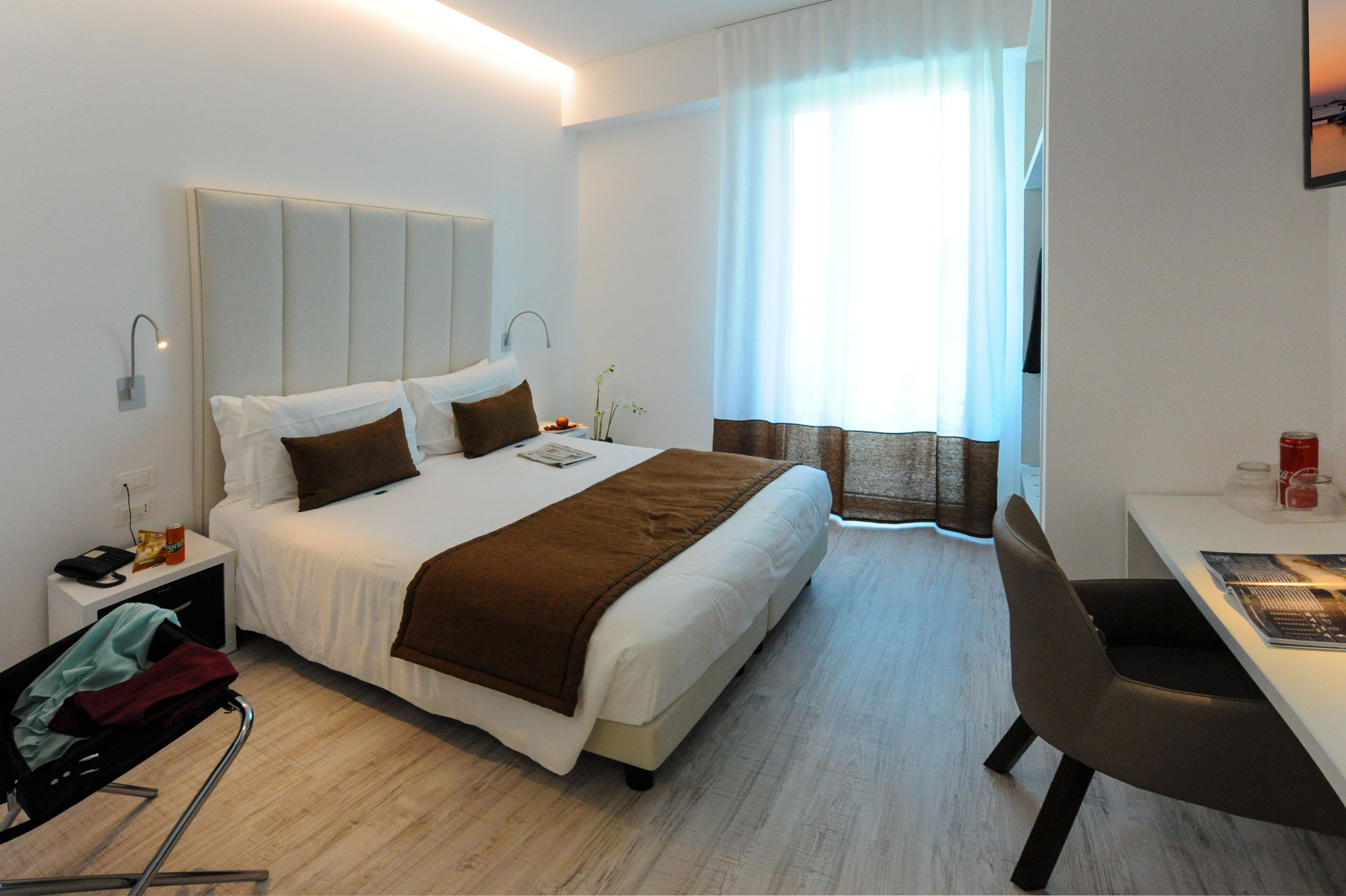Ett modernt hotellrum med en stor säng, ett skrivbord och en stol.