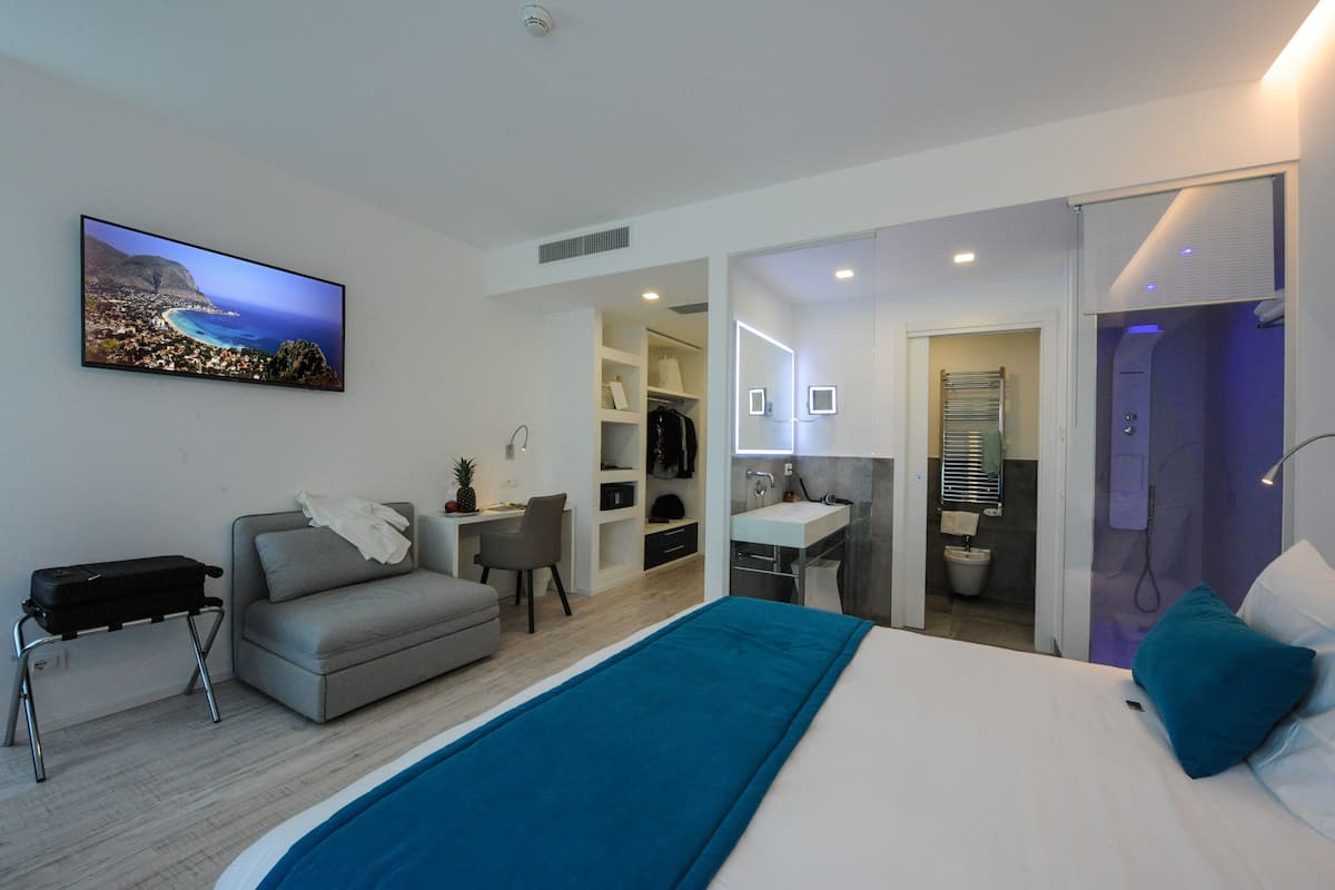 Een moderne hotelkamer met een bed, een bureau, een slaapbank en een badkamer.