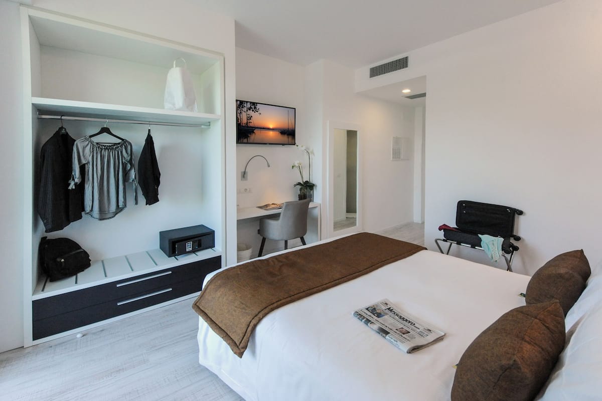 Een moderne hotelkamer met een bed, een bureau en een kledingkast.