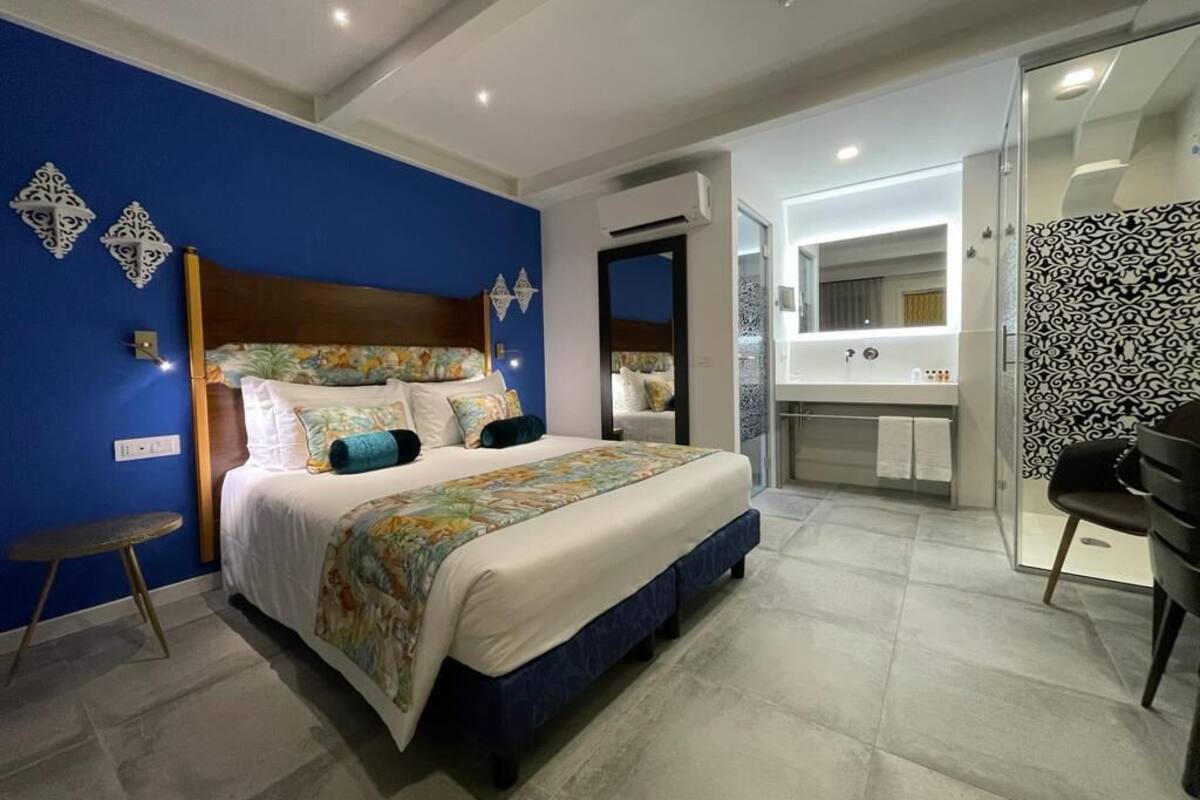 Een moderne hotelkamer met een groot bed, een badkamer met spiegel en een klein tafeltje.