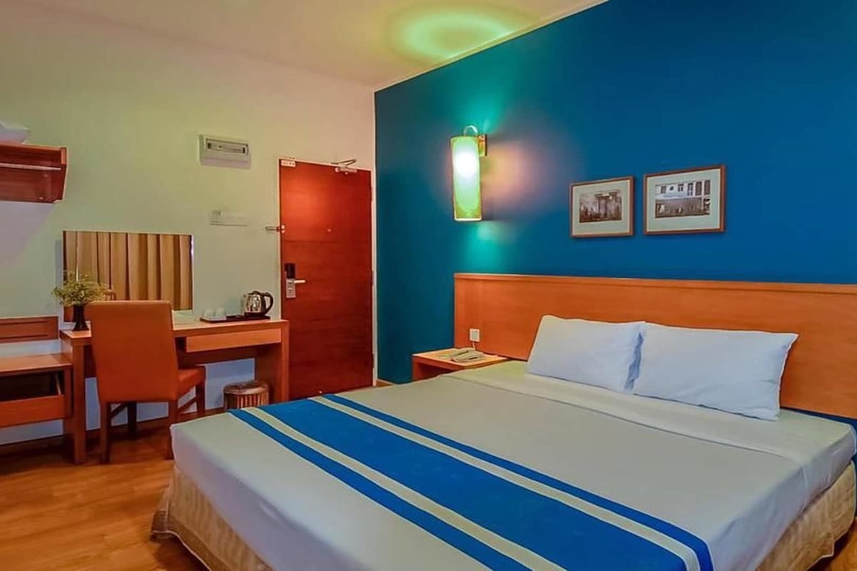 A hotel room with a bed, a desk, and a chair.