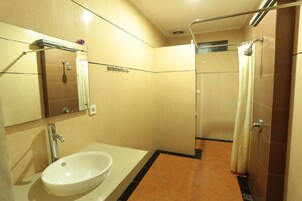 Un bagno con lavandino, specchio, doccia e pareti piastrellate.