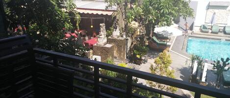 A poolside area with a stone structure, lounge chairs, and a statue.