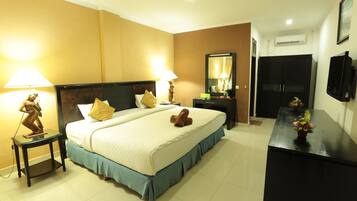 A hotel room with a large bed, two bedside tables with lamps, a dresser, a mirror, and a TV on the wall.