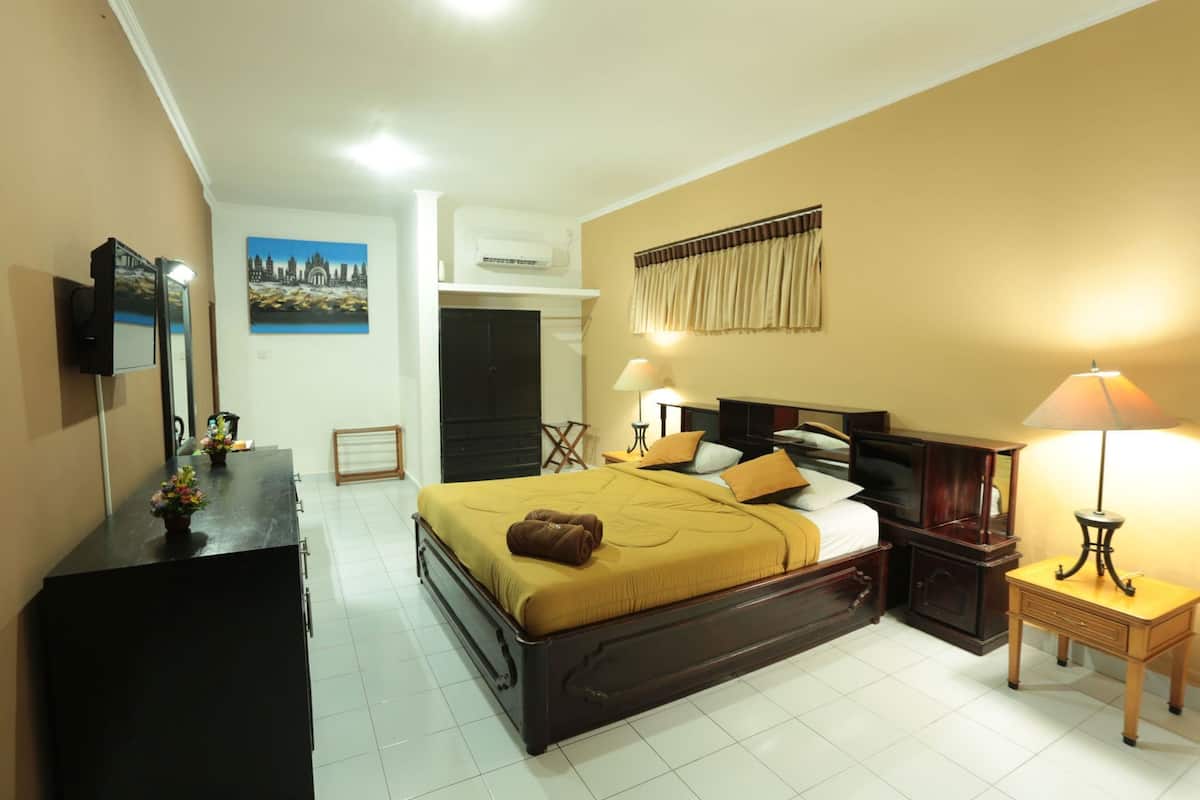 Habitación de hotel con cama, mesitas de noche, cómoda, televisor y un cuadro en la pared.