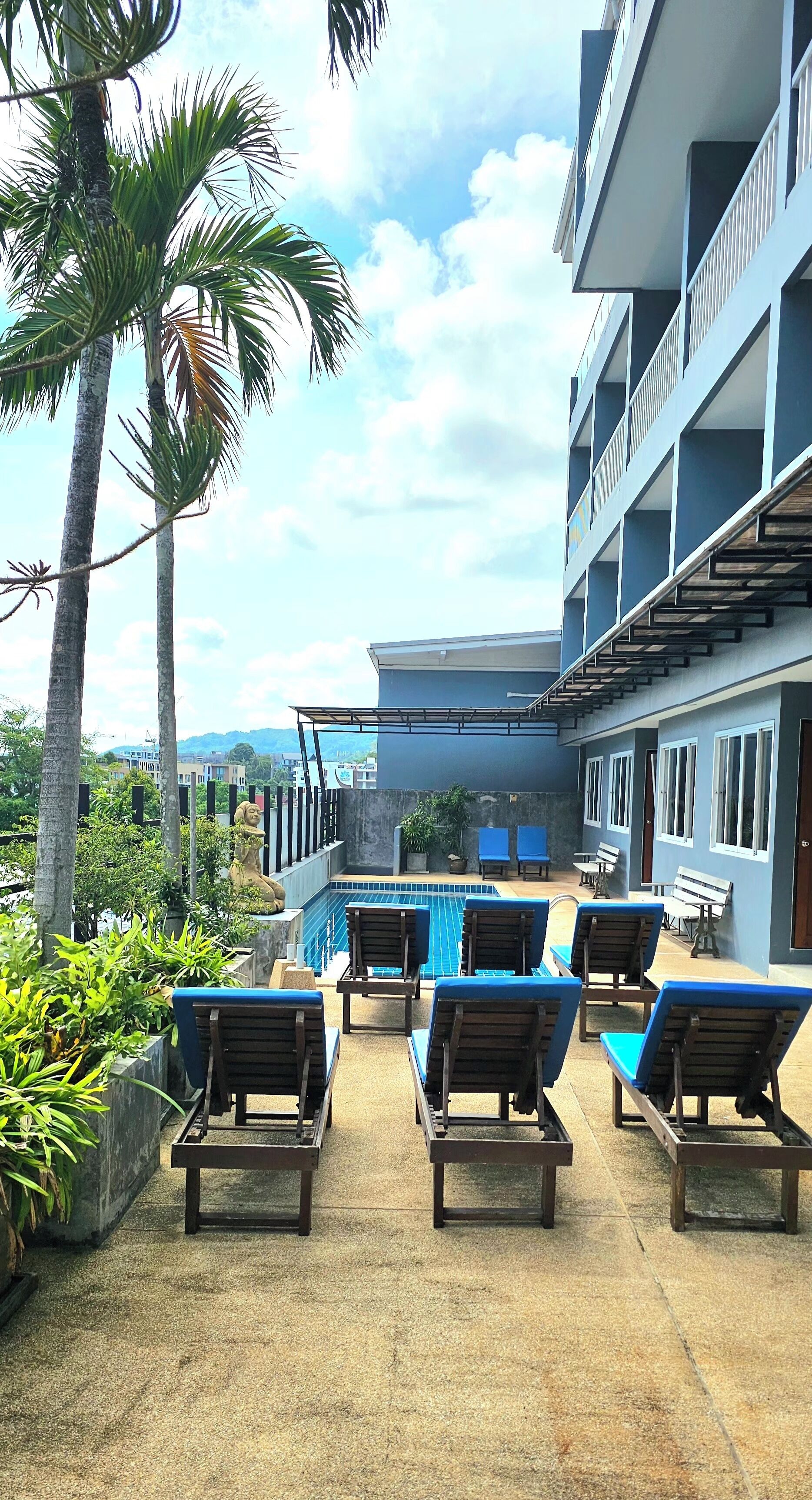 Un espace aménagé au bord de la piscine, avec des chaises longues, une piscine et un bâtiment doté de balcons.