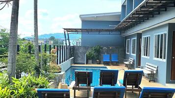 Un espace aménagé au bord de la piscine, avec des chaises longues, une piscine et un bâtiment doté de balcons.