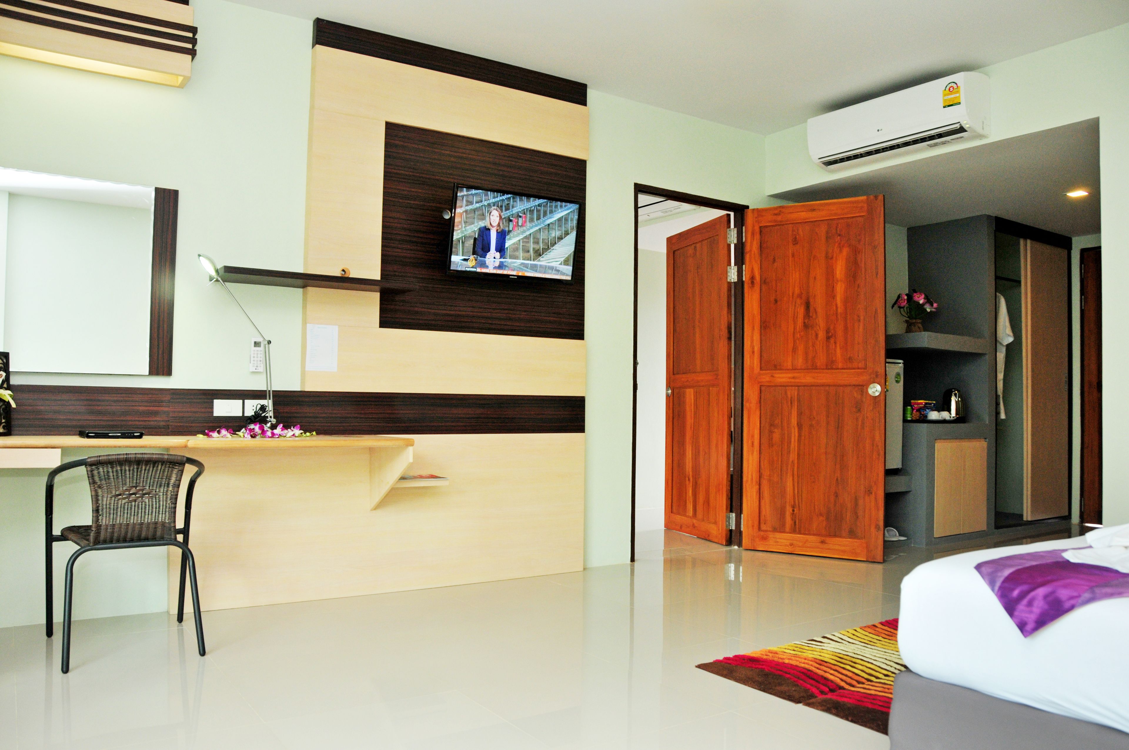 A hotel room with a desk, chair, bed, and an open door leading to a bathroom.