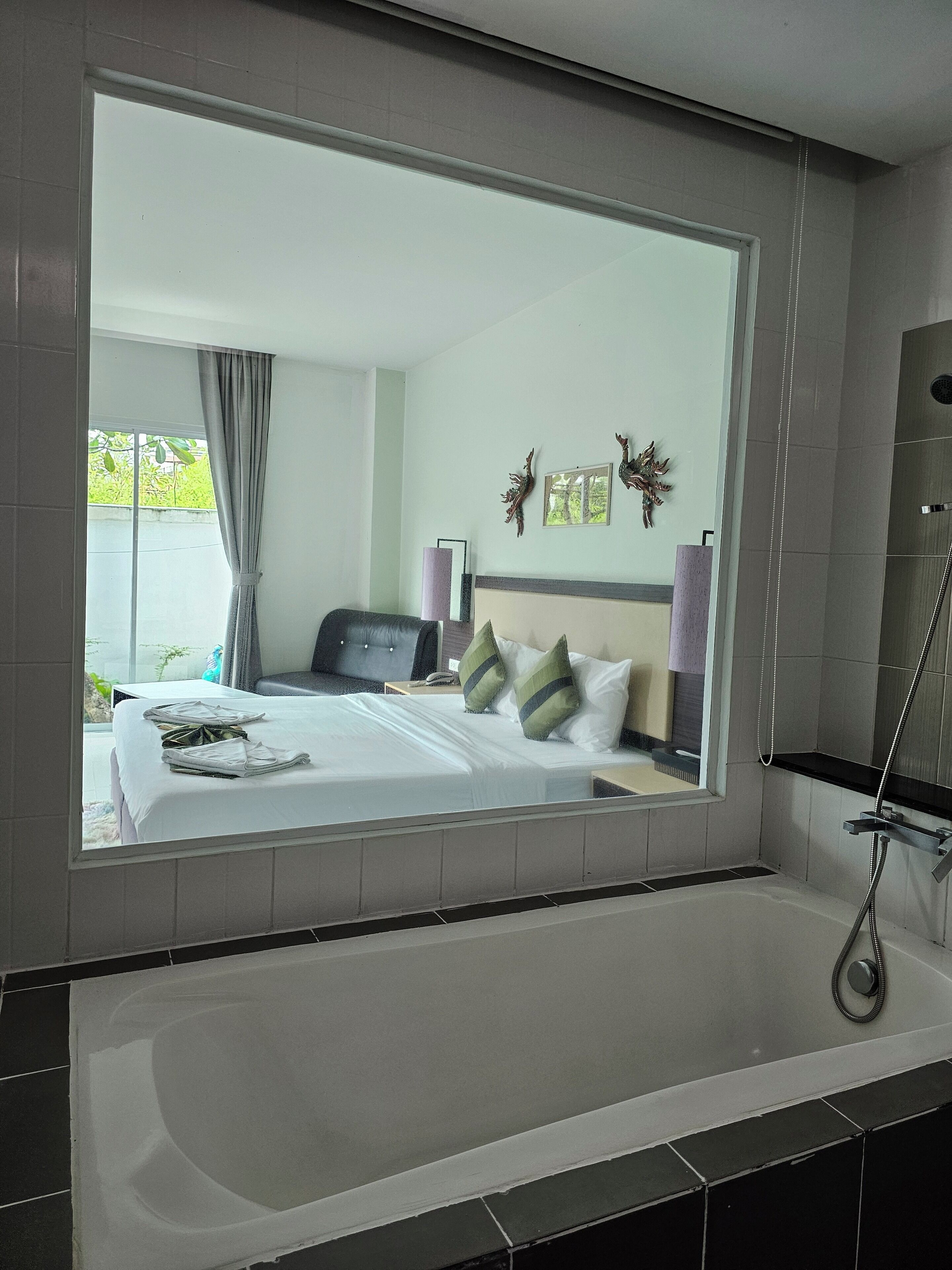 Ein modernes Badezimmer mit einer großen Badewanne, einer Dusche und einem Bett mit Blick ins Freie.