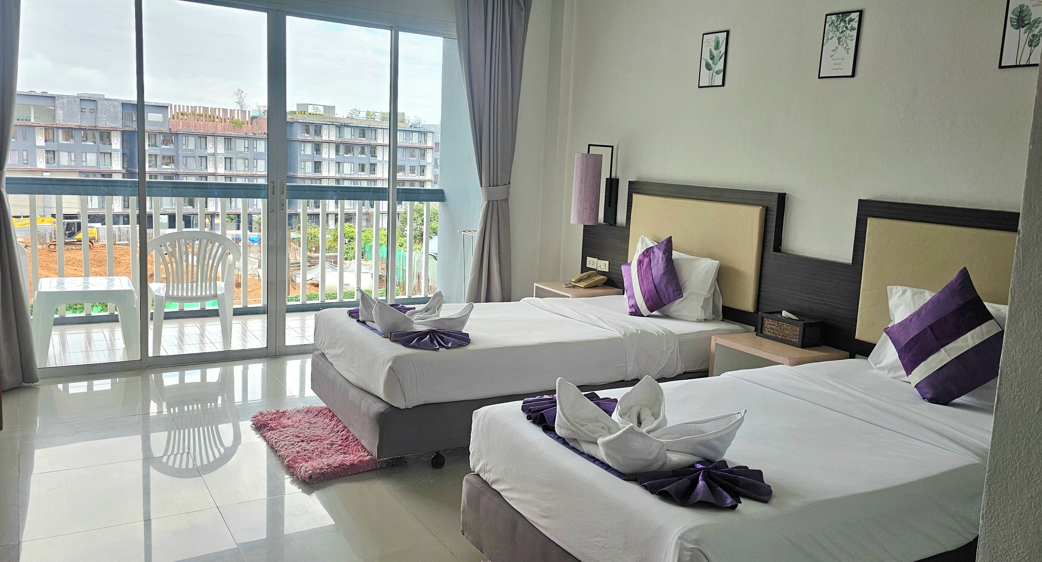 A hotel room with two beds, a large window, and a view of buildings outside.