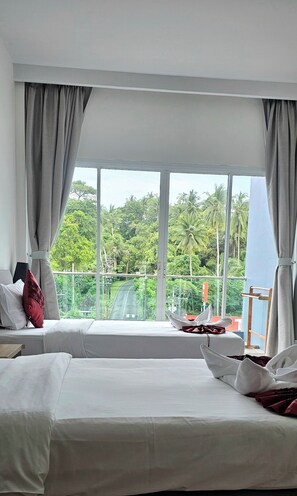A hotel room with two beds, large windows, and a view of a lush green landscape.