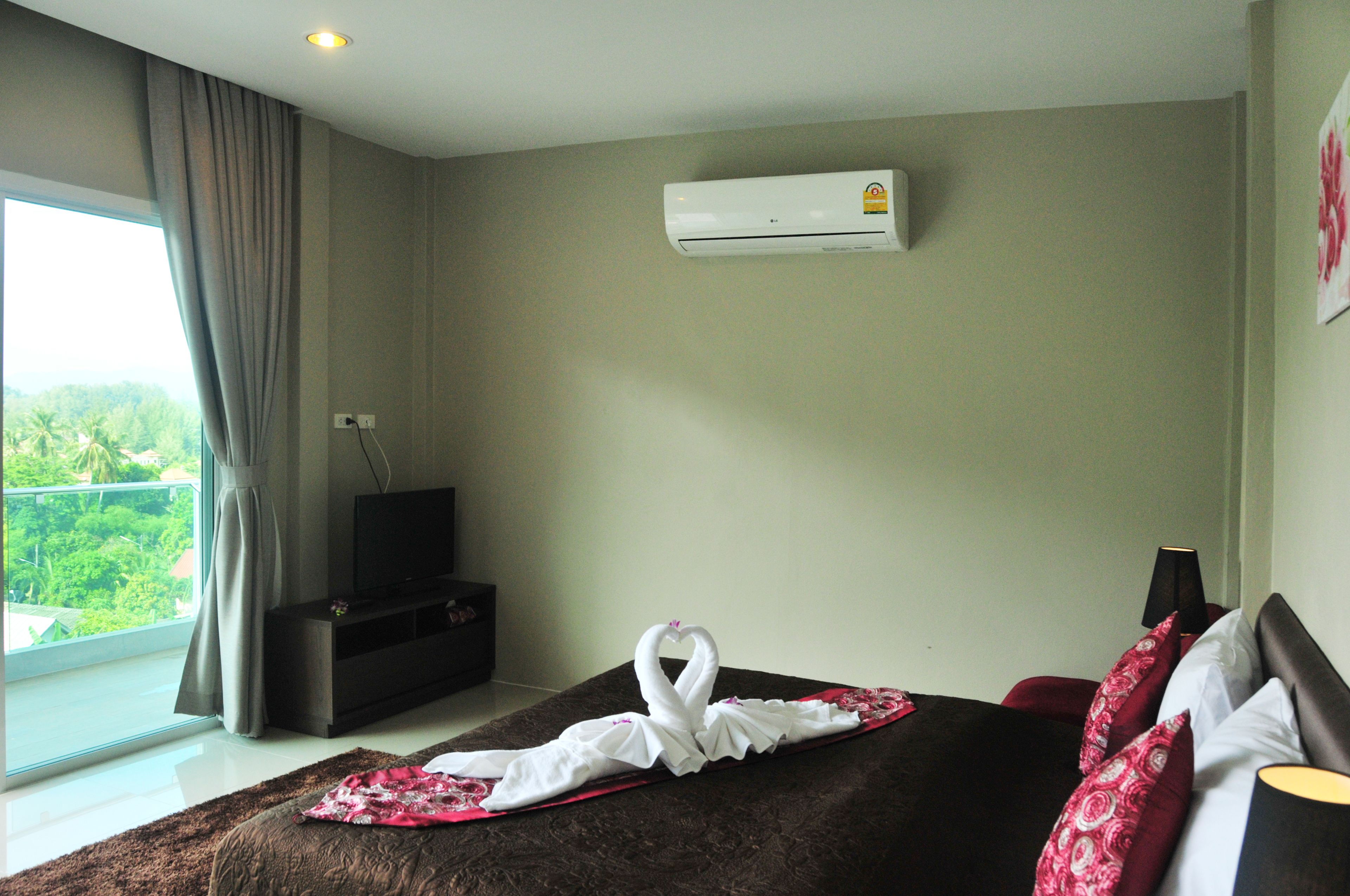 Ein Hotelzimmer mit Bett, Fernseher, Klimaanlage und Blick auf Grün.
