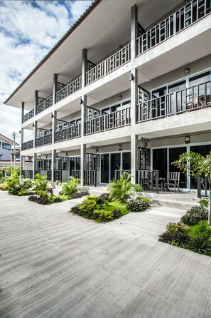 Un hôtel à plusieurs étages doté de balcons, de grandes fenêtres et d’une cour aménagée.