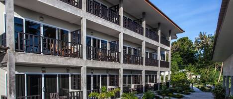 A multi-story hotel with balconies, large windows, and a landscaped courtyard.