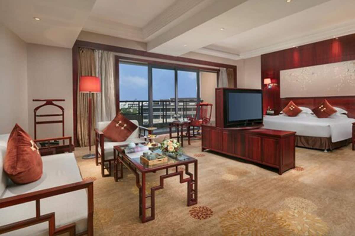 Une chambre d’hôtel avec un lit, une télévision, un bureau et un balcon offrant une vue.