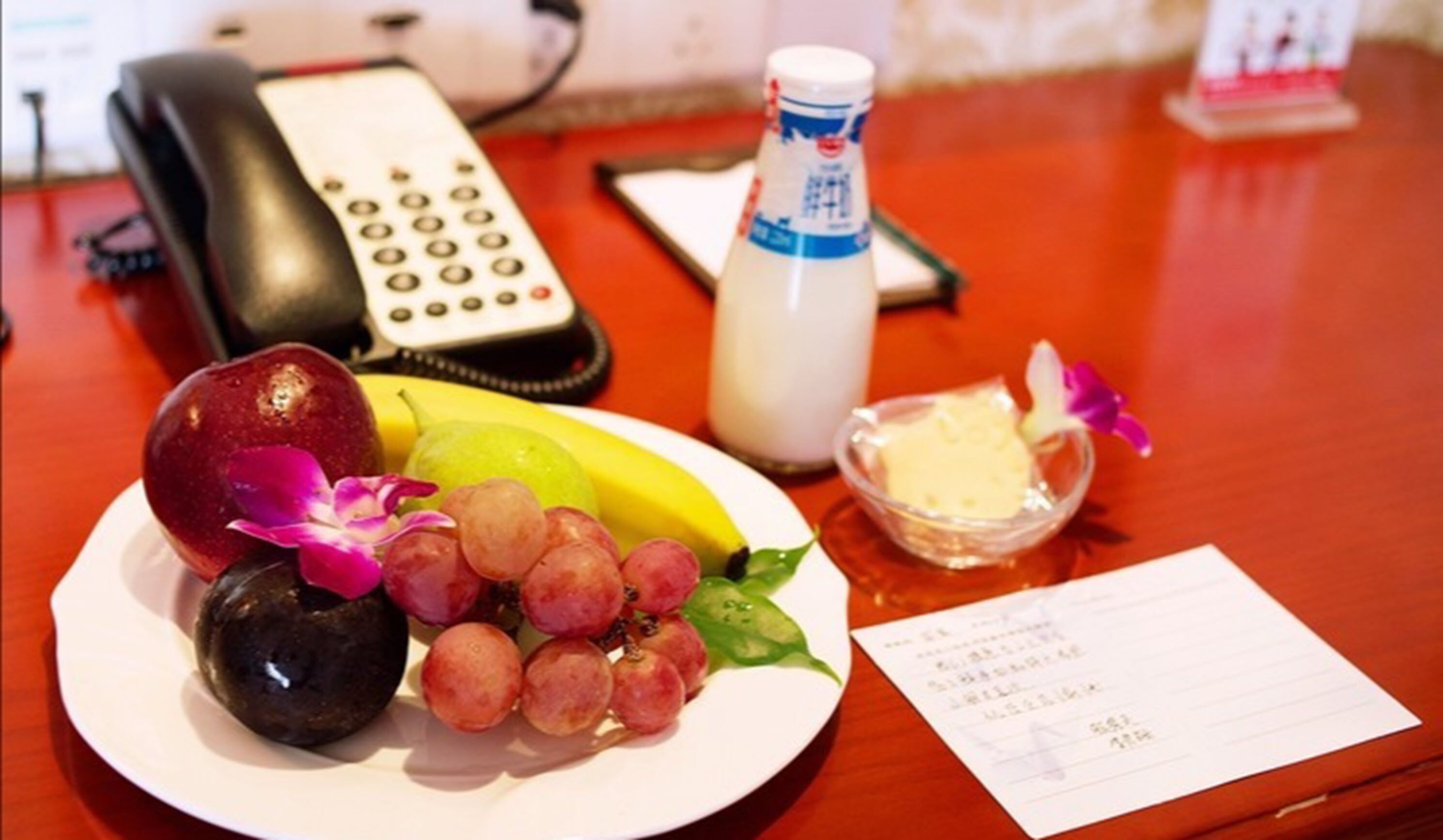 A plate with fruits and a bottle of milk on a wooden table.