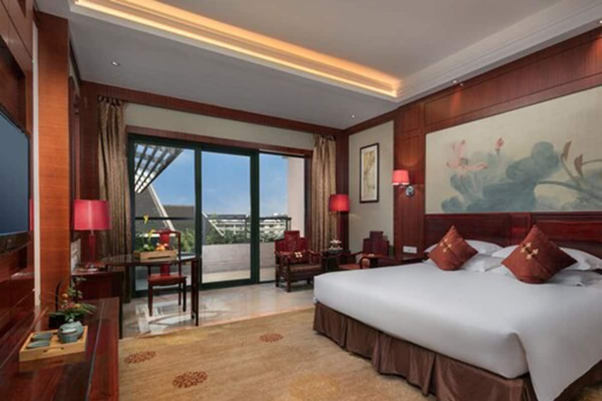Une chambre d’hôtel avec un grand lit, un bureau avec une chaise, une télévision et un balcon avec vue.