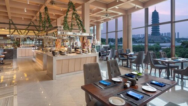 Um restaurante espaçoso com pé-alto, grandes janelas e vista para um pagode.