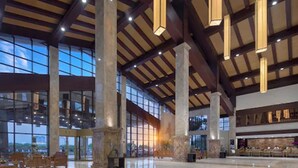 Um hall amplo com pé-direito alto, grandes janelas e luminárias modernas.