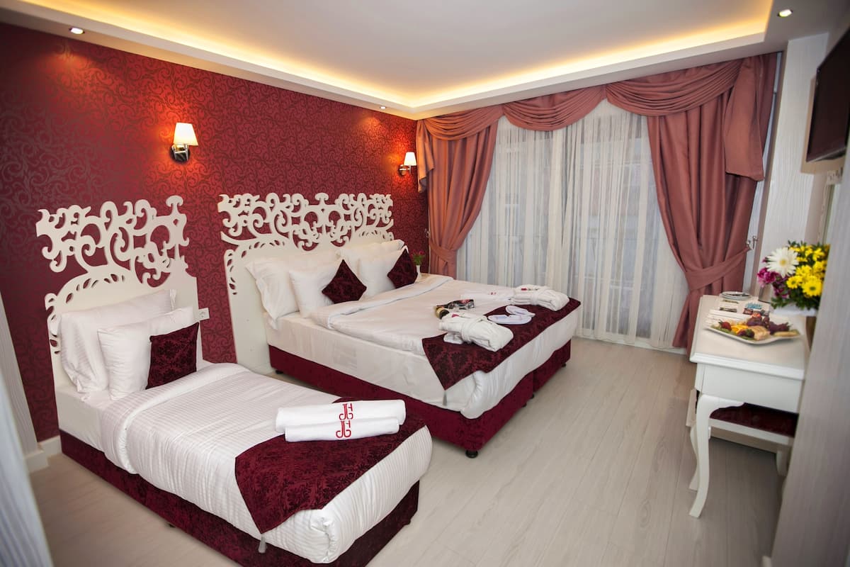 A hotel room with two beds, a desk, and a mirror.