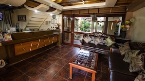 Un espace d’accueil comprenant un comptoir de réception en bois, un canapé en cuir et une table basse.