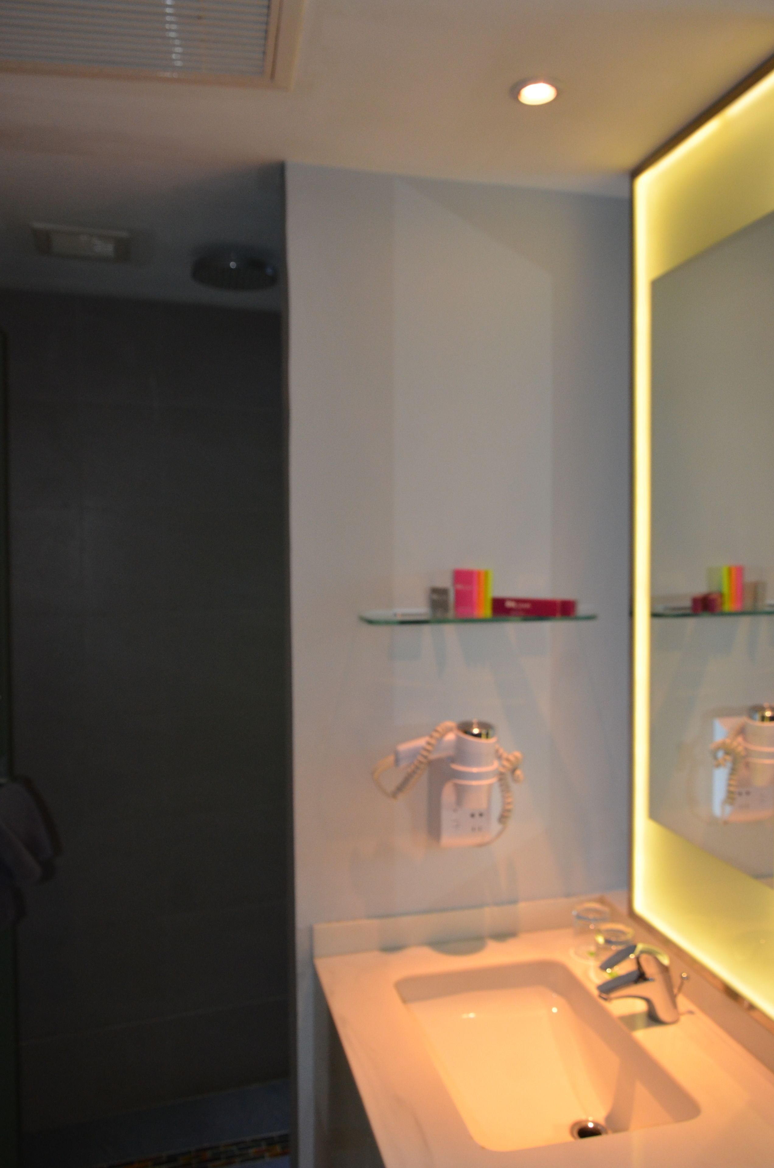 Ein Badezimmer mit Waschbecken, Spiegel und Ablagen für Toilettenartikel.
