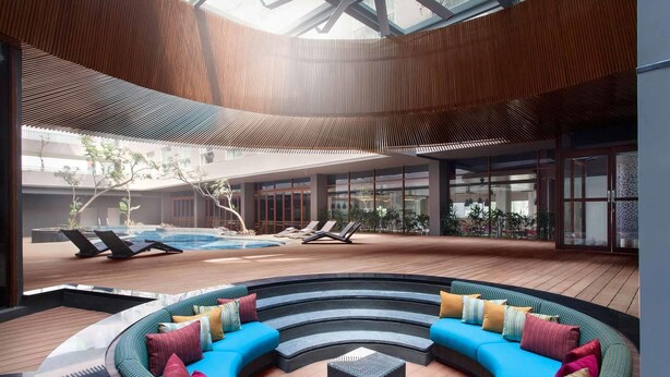 A modern indoor pool area with a circular seating area, lounge chairs, and a glass ceiling. - ibis Styles Jakarta Airport (Tangerang)