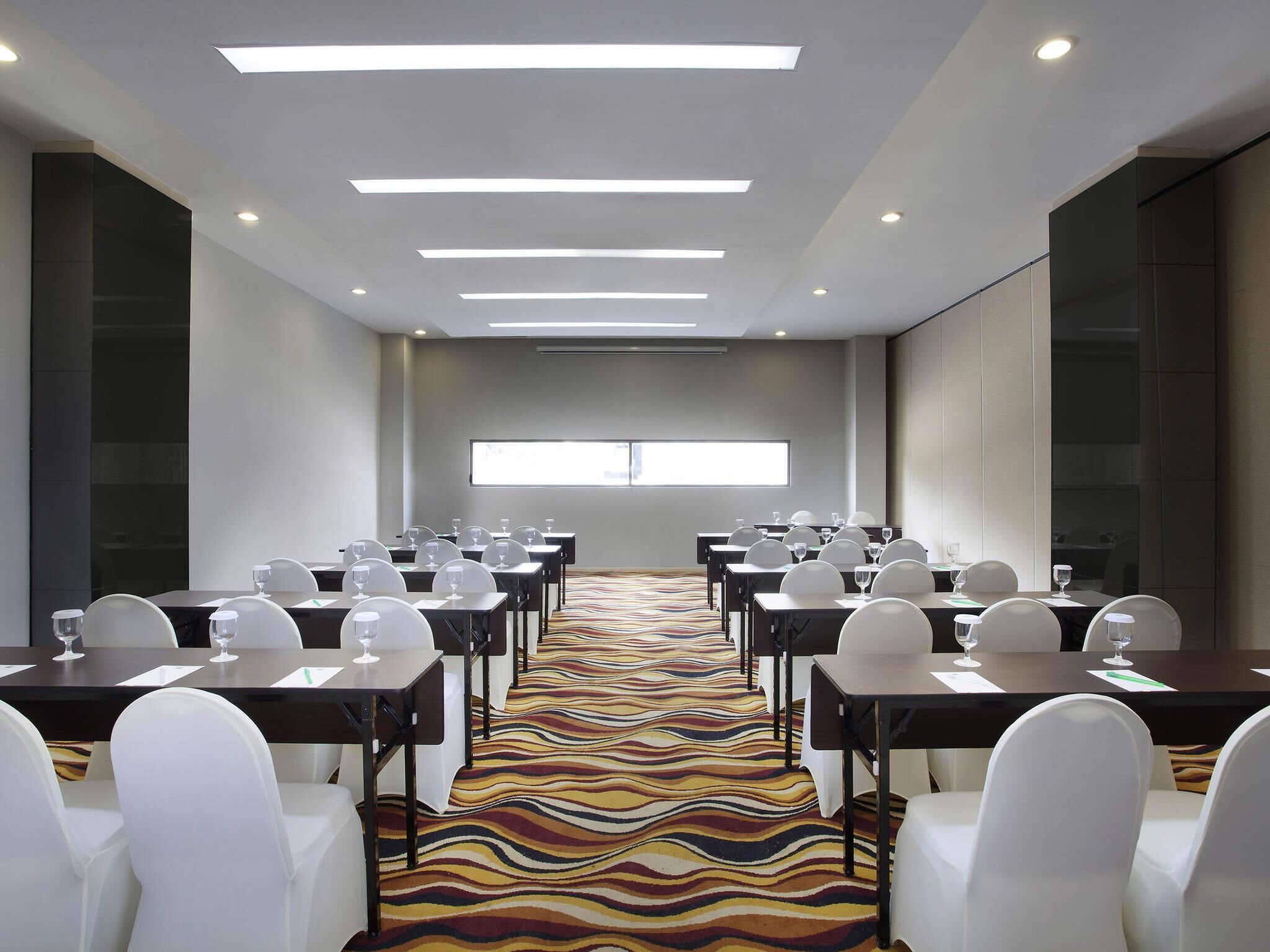 A conference room with tables, chairs, and a patterned carpet.