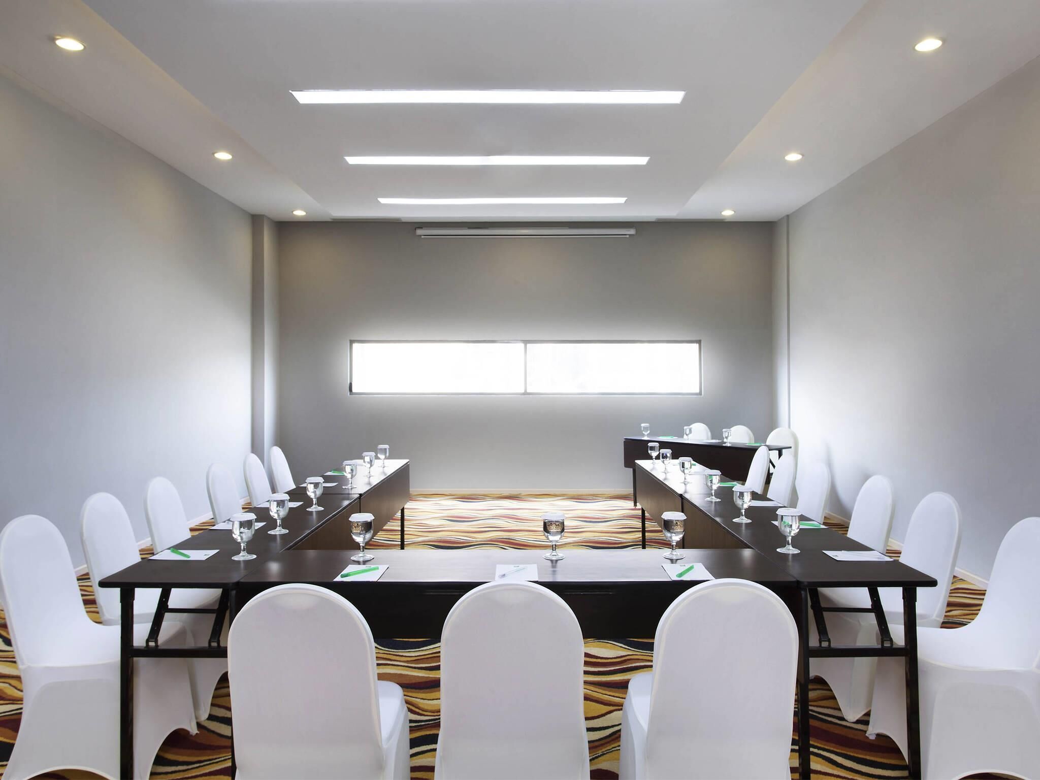 A conference room with a long table, white chairs, and a large window.