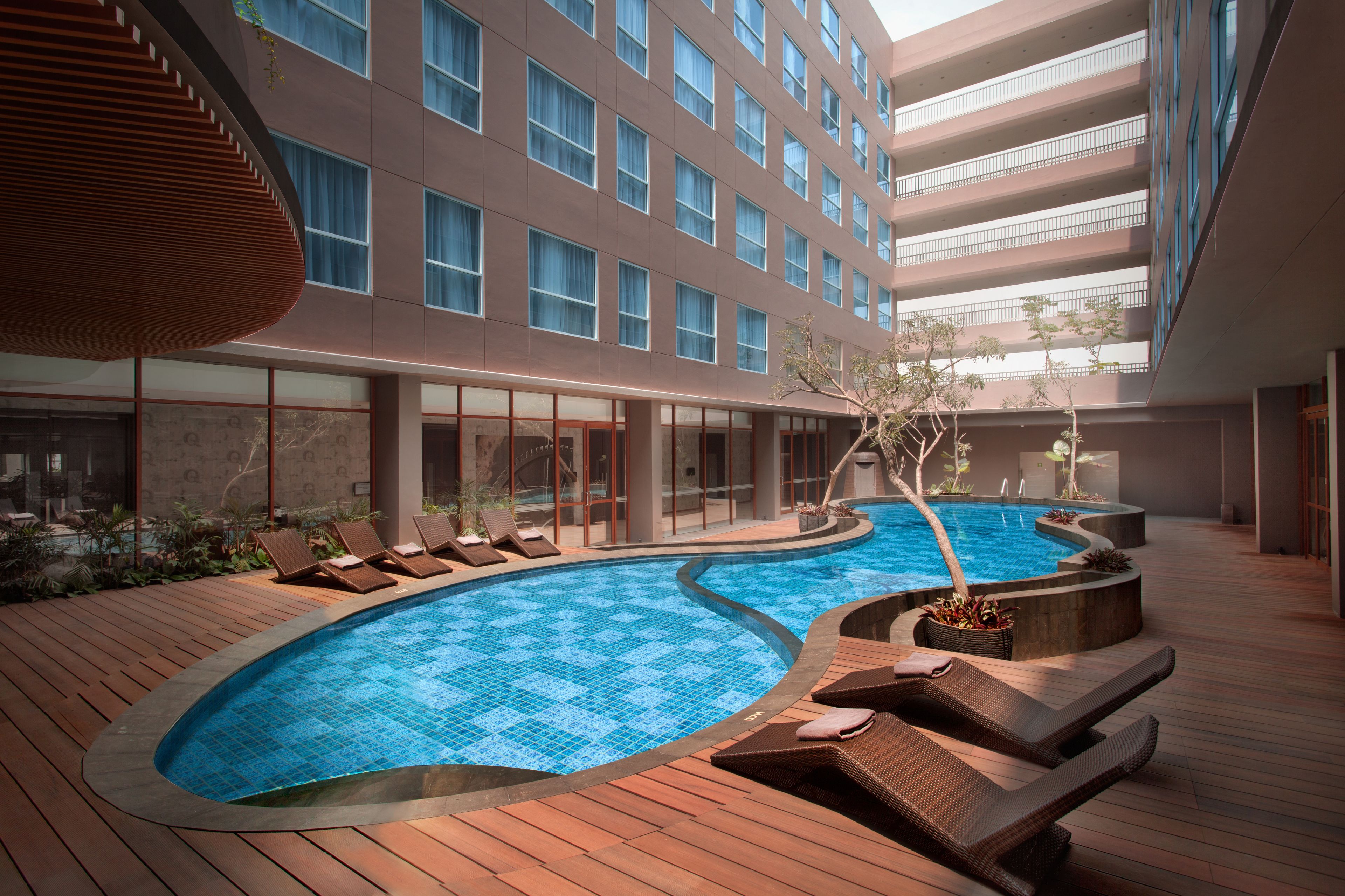 Um hotel moderno com piscina no terraço, espreguiçadeiras e vista para a fachada do edifício.