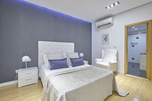 A modern bedroom with a large bed, bedside tables, a chair, and a wardrobe. - Apartamentos en Sol (Madrid)
