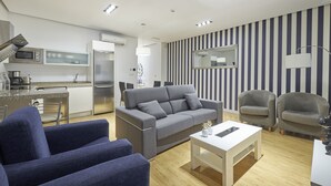 Ein modernes Wohnzimmer mit einem grauen Sofa, zwei Sesseln, einem weißen Couchtisch und einer gestreiften Wand.